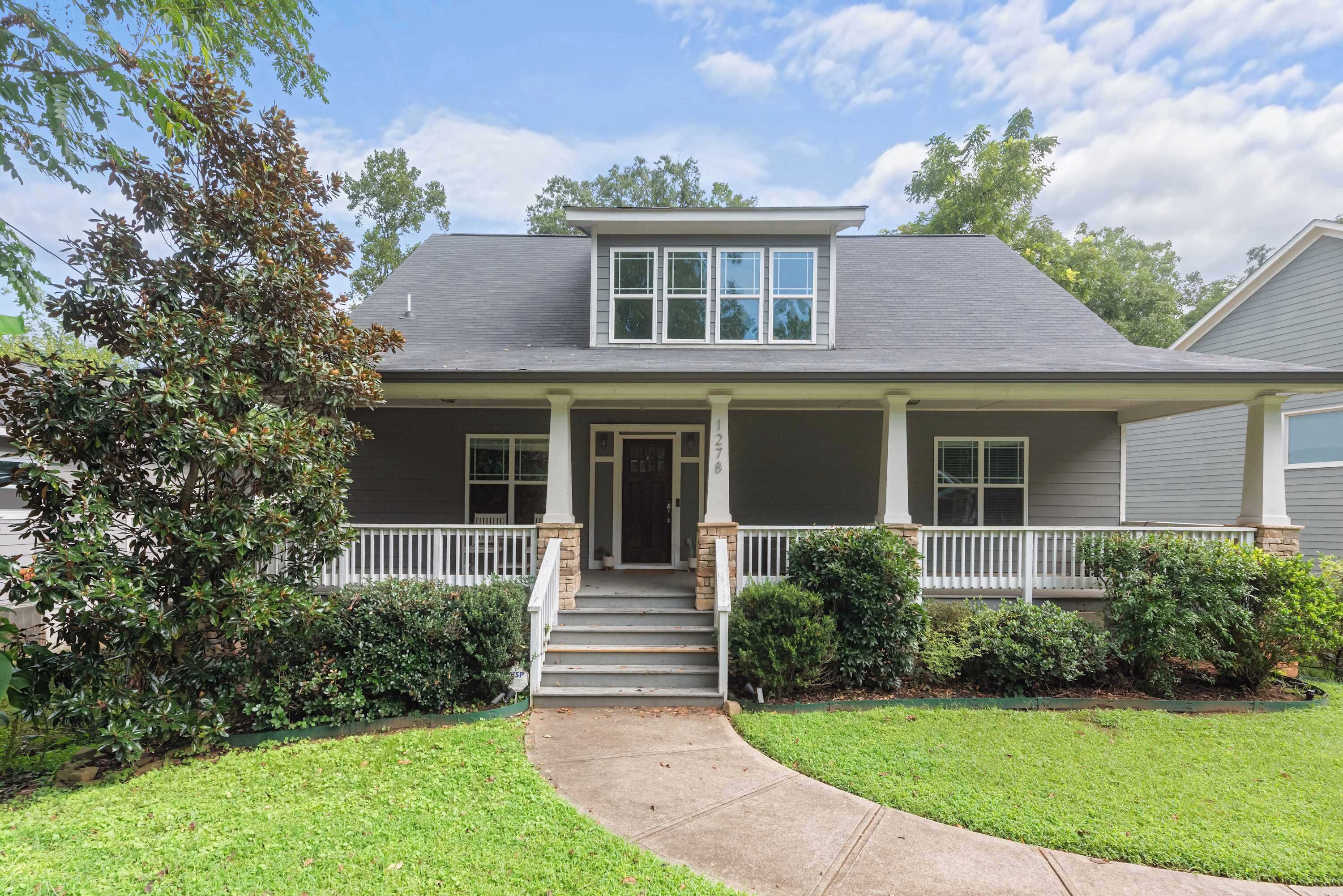 A two-story house with a front porch, a covered entryway, and a small front yard.