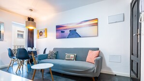 Ein modernes Wohnzimmer mit einer Couch, Sesseln, einem Esstisch und Kunstwerken an der Wand.