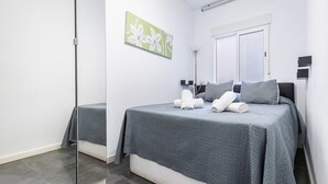 Ein Schlafzimmer mit einem Bett, einem Spiegel, einem Fenster und einem Bild an der Wand.