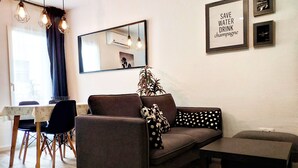 Una sala moderna con un sofá, una mesita, un comedor con sillas y un espejo en la pared.