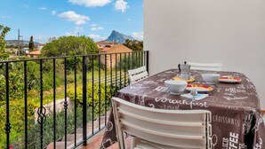 A balcony with a table set for breakfast, a mountain view, and a railing.