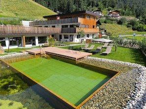 Un hotel moderno con piscina, area salotto esterna e vista sulle colline circostanti.