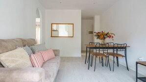 A modern living room with a sofa, a dining table with chairs, a mirror on the wall, and a vase with flowers. - Holiday Home "Yolima" near the Beach with Wi-Fi, Air Conditioning and Garden (Sóller)