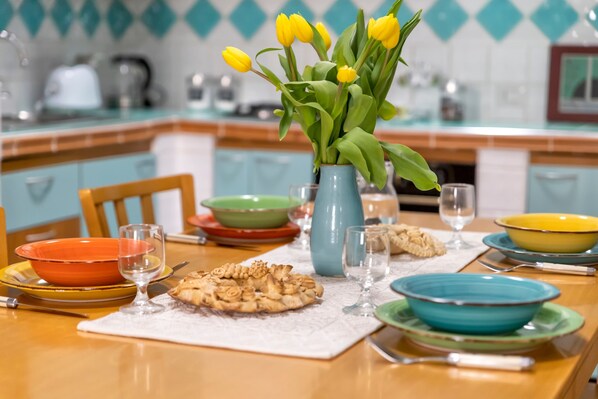 Une table à manger ornée d’un vase de tulipes jaunes, de différents plats et de verres.