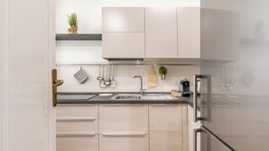Una cocina moderna con un refrigerador de acero inoxidable, un fregadero y armarios de color claro.