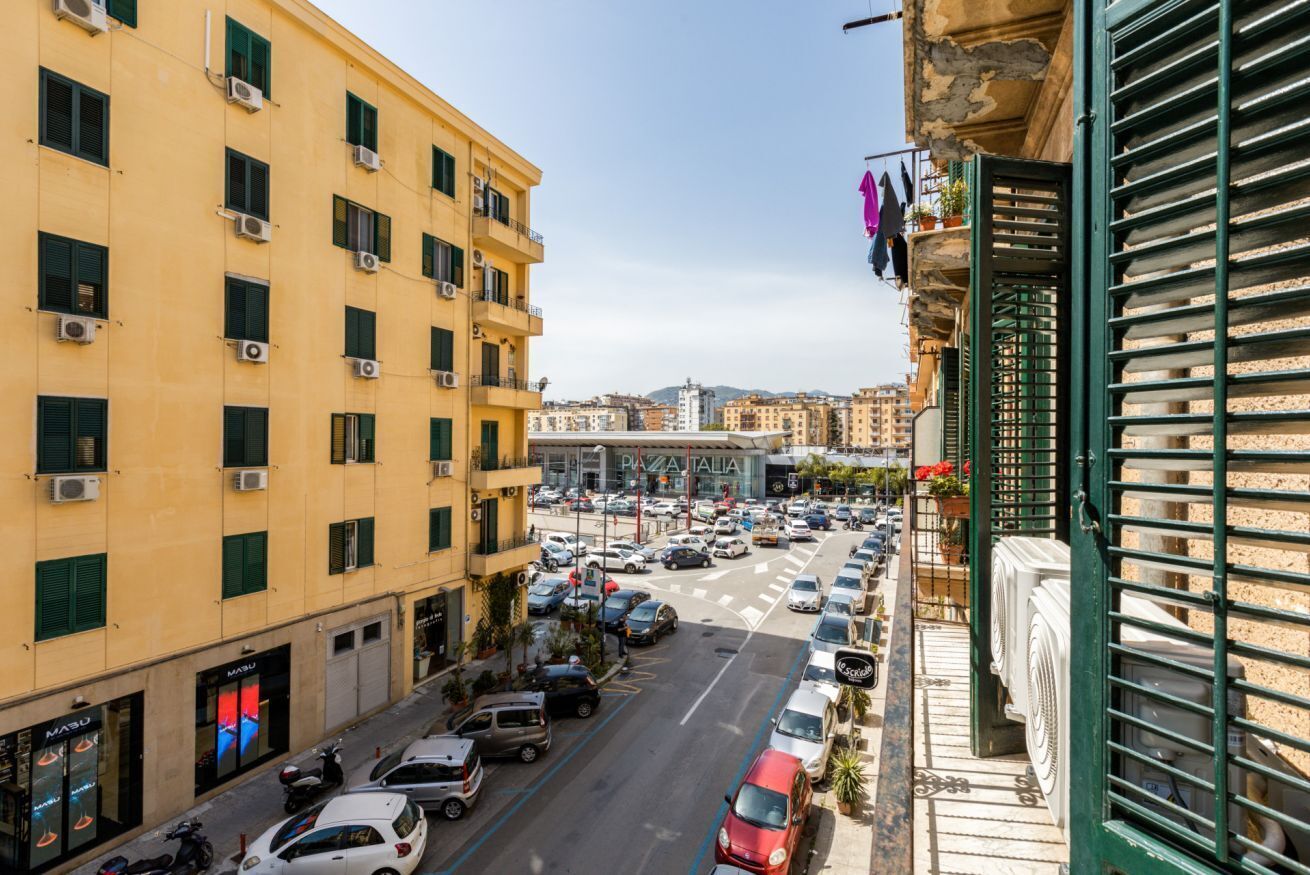 A street view with a yellow building, parked cars, and a visible storefront with a sign.