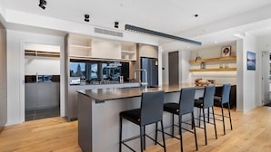 A modern kitchen with a central island, bar stools, and a view of the city.