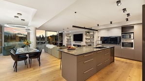A modern kitchen with a central island, built-in appliances, and a dining area with a view of the mountains.