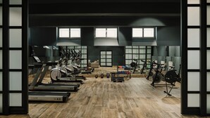 Une salle de sport équipée de tapis de course, de vélos elliptiques et de poids libres.