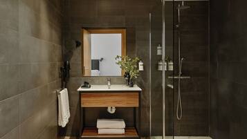 Un baño moderno con tocador de madera, cabina de ducha de vidrio y un espejo grande.