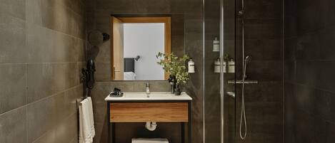 A modern bathroom with a wooden vanity, a glass shower enclosure, and a large mirror.