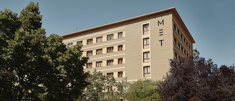 A multi-story building with the letters "MET" on the facade, surrounded by trees and a clear sky.