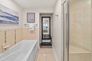 Ein modernes Badezimmer mit einer Badewanne, einer Dusche und einem gerahmten Kunstwerk an der Wand.