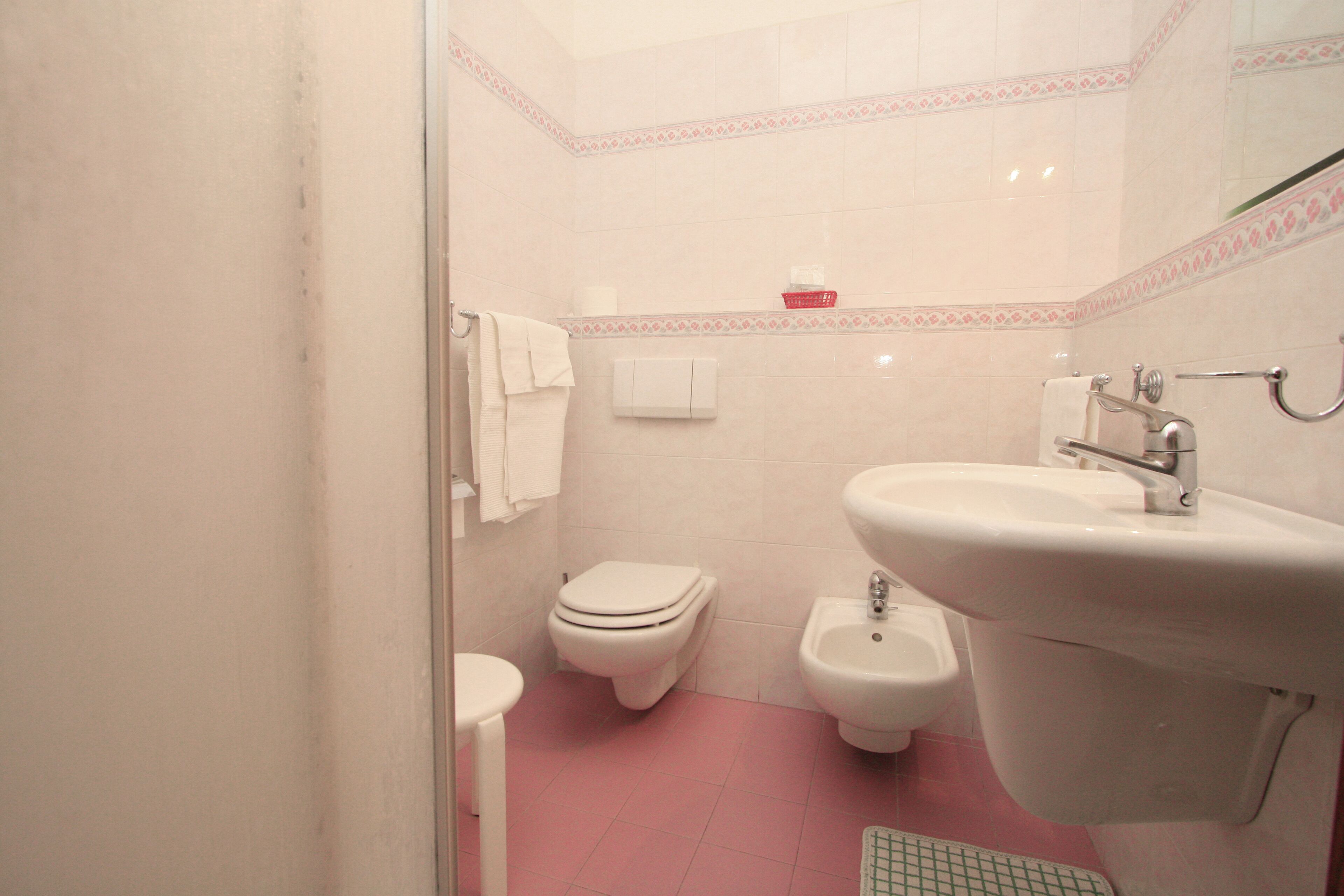A bathroom with a toilet, bidet, sink, and a mirror.