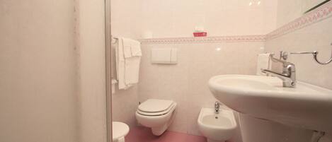 A bathroom with a toilet, bidet, sink, and a mirror.