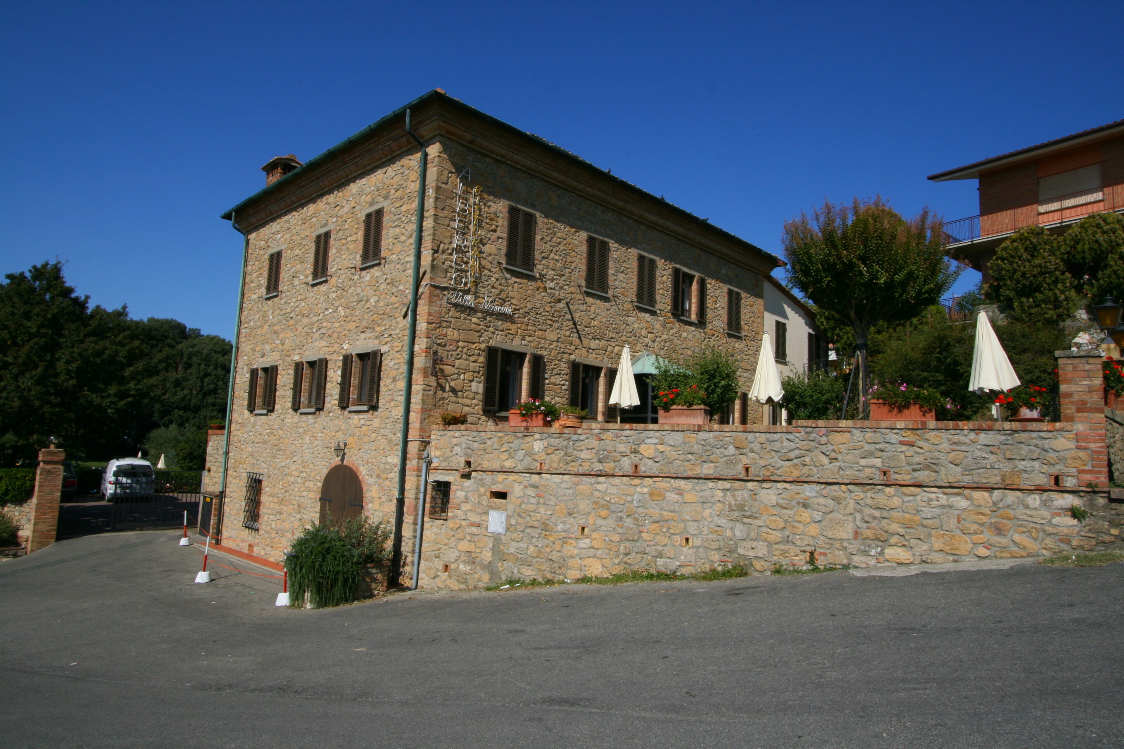 A stone building with a balcony, outdoor seating, and a stone wall.