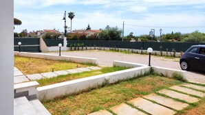 A residential area with a paved driveway, a car parked on the street, and a green fence. - iPesci di Sperlonga B&B 200 meters from the sea (Sperlonga)