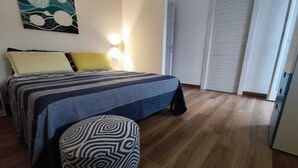 A bedroom with a bed, a bedside table, a chair, a wall painting, and a door. - iPesci di Sperlonga B&B 200 meters from the sea (Sperlonga)