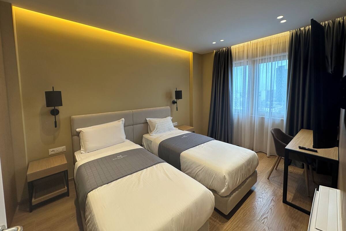 A hotel room with two beds, a desk, and a chair.