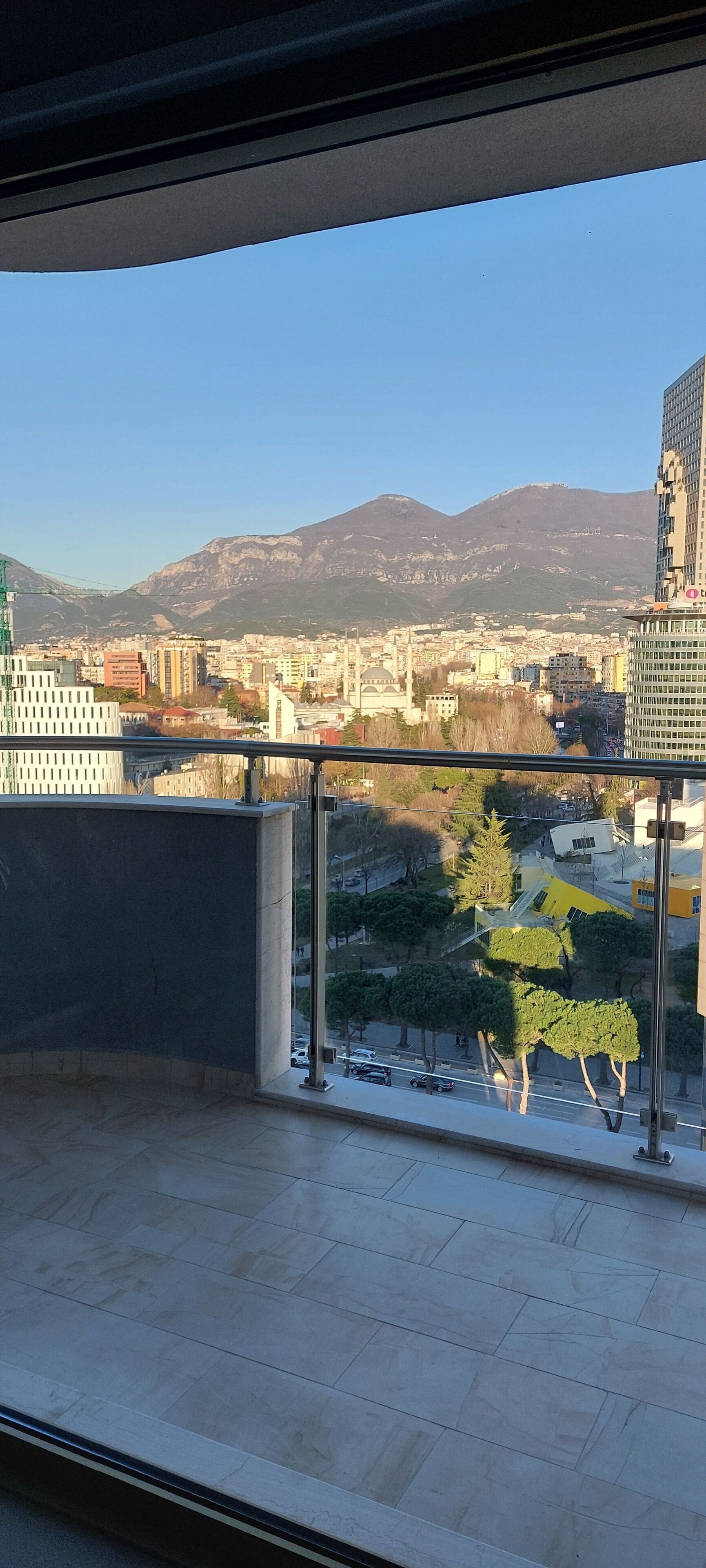 Un balcon offrant une vue sur le paysage urbain, avec des bâtiments et une montagne en arrière-plan.