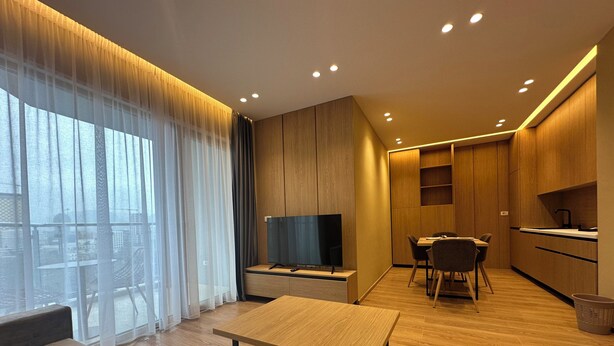 Una sala de estar moderna con un sofá, una mesa de centro, un televisor y un comedor con una mesa y sillas.