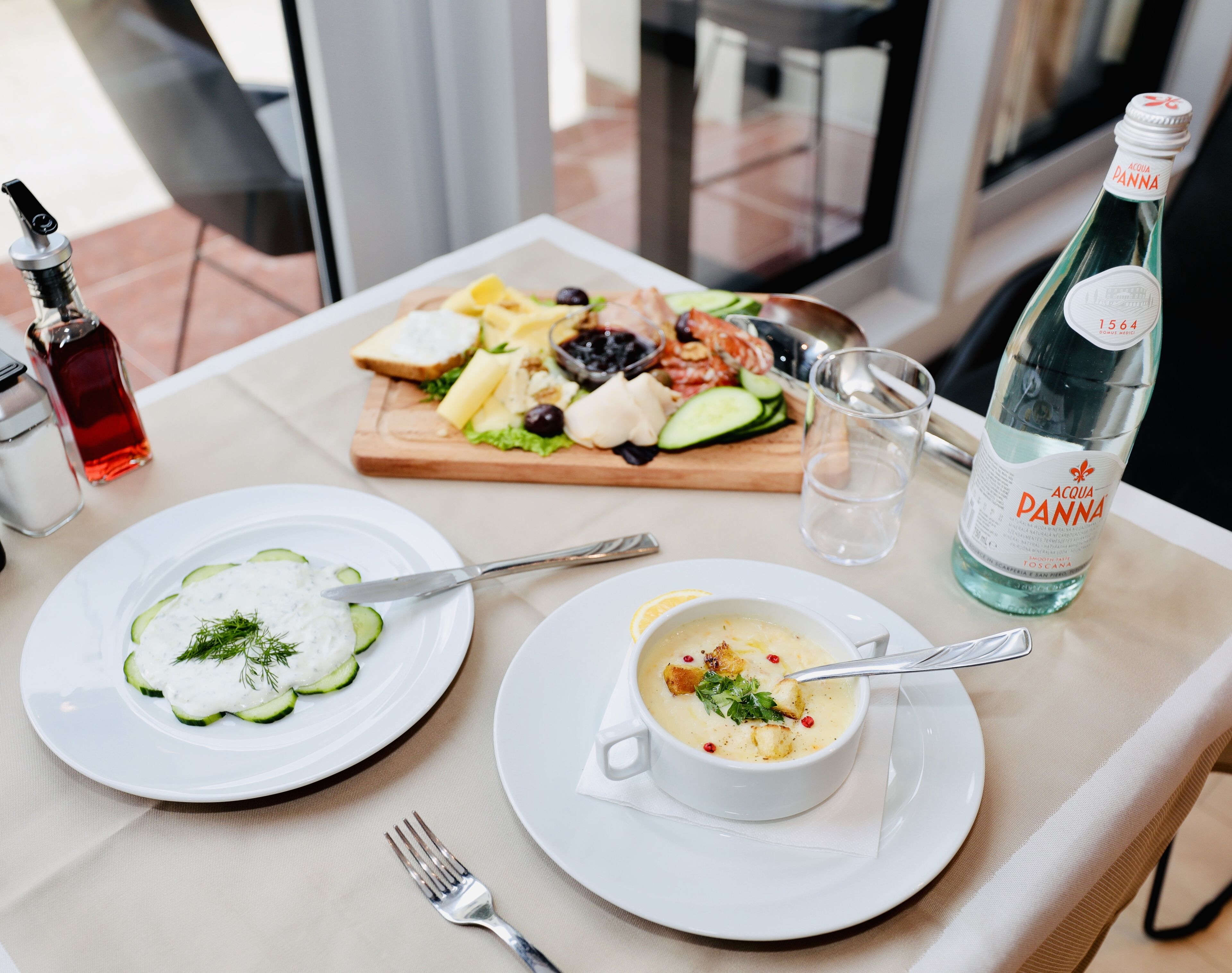 A table with two plates of food, a bottle of water, and a salt shaker.