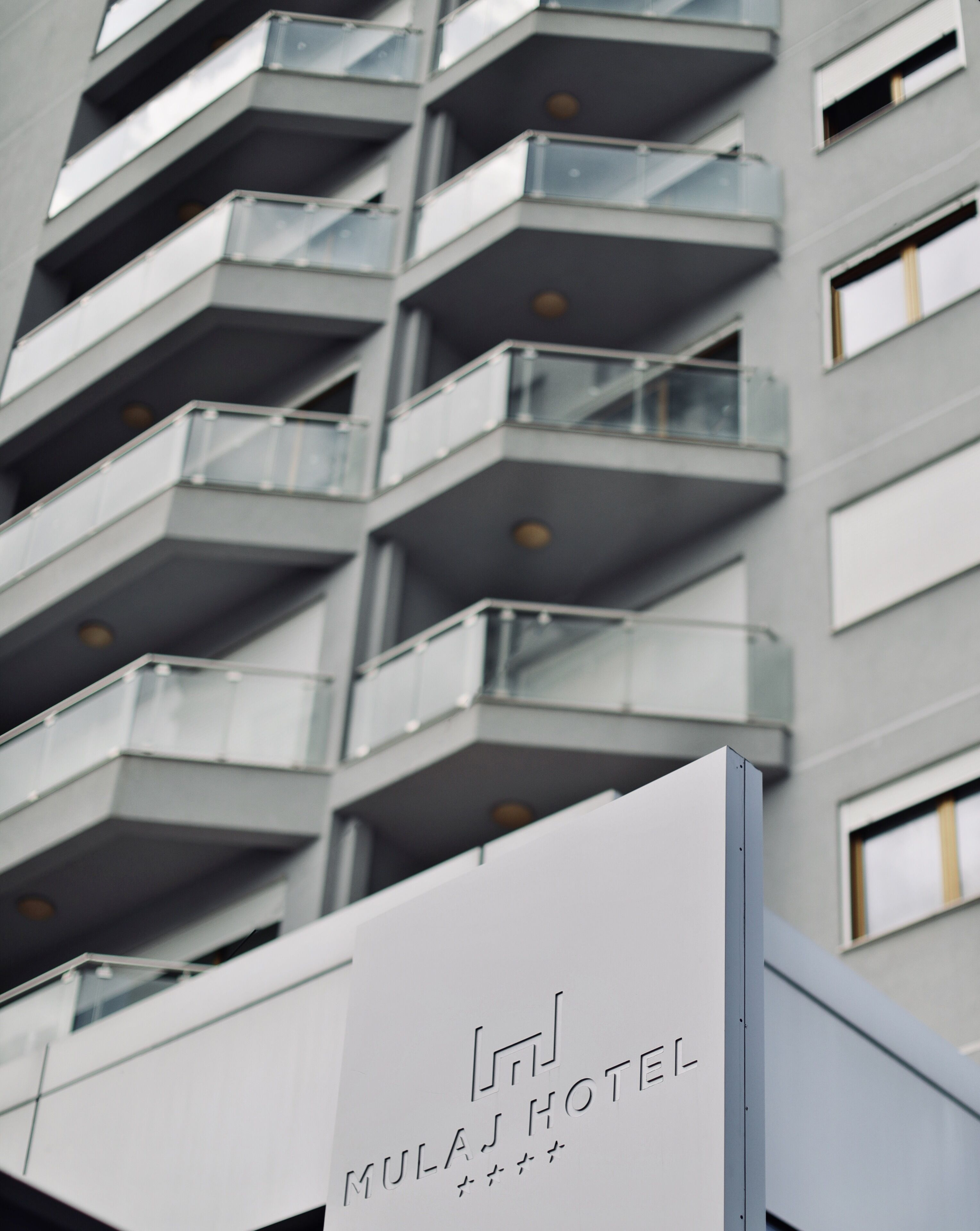 Moderni hotellirakennus, jossa on useita parvekkeita ja kyltti, josta ilmenee, että kyseessä on Mulan-hotelli.