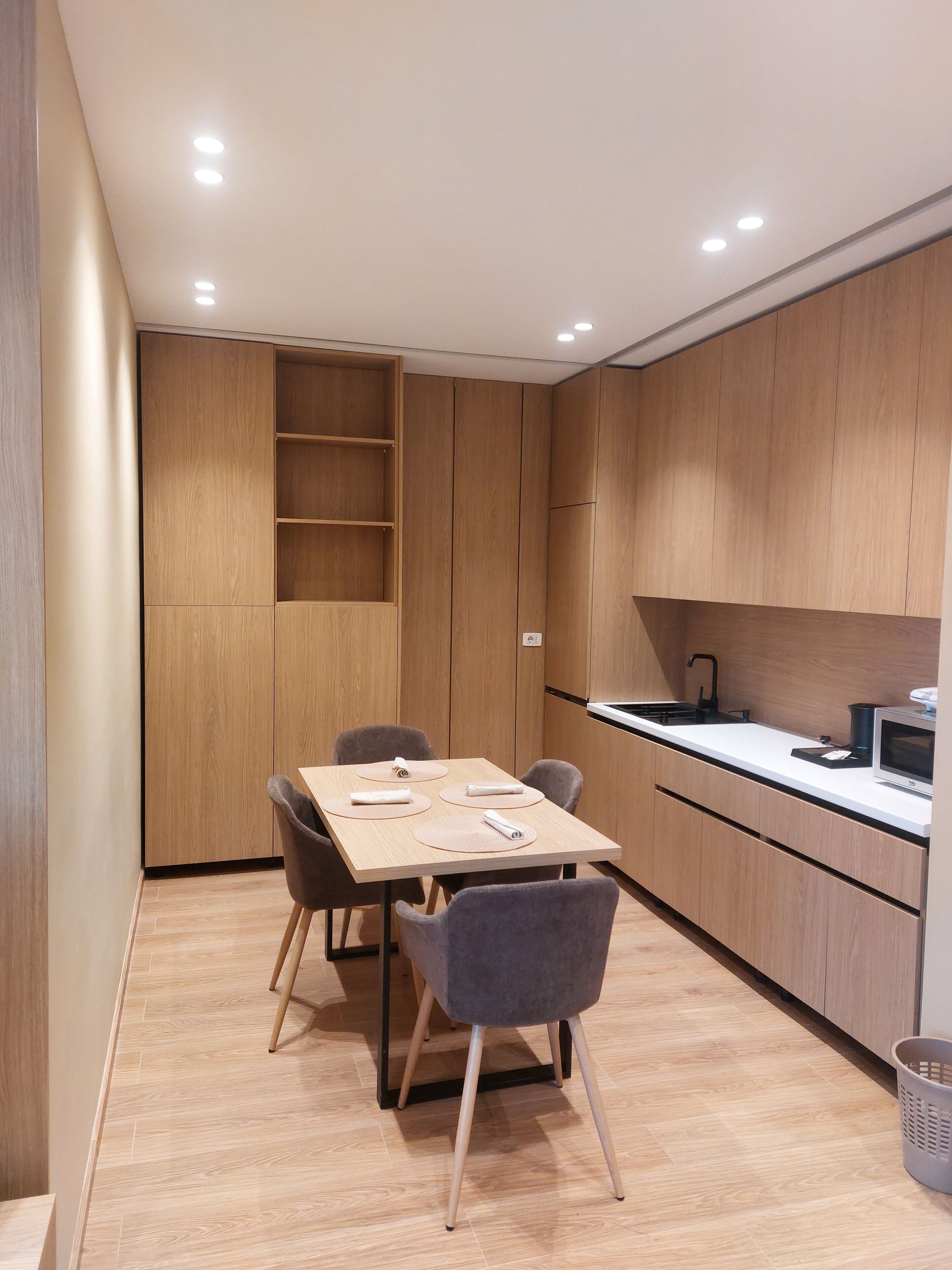 Una cocina moderna con armarios de madera, una mesa de comedor con sillas y un microondas.