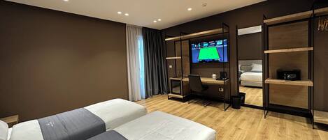 A modern hotel room with two beds, a desk, a TV, and built-in shelves.