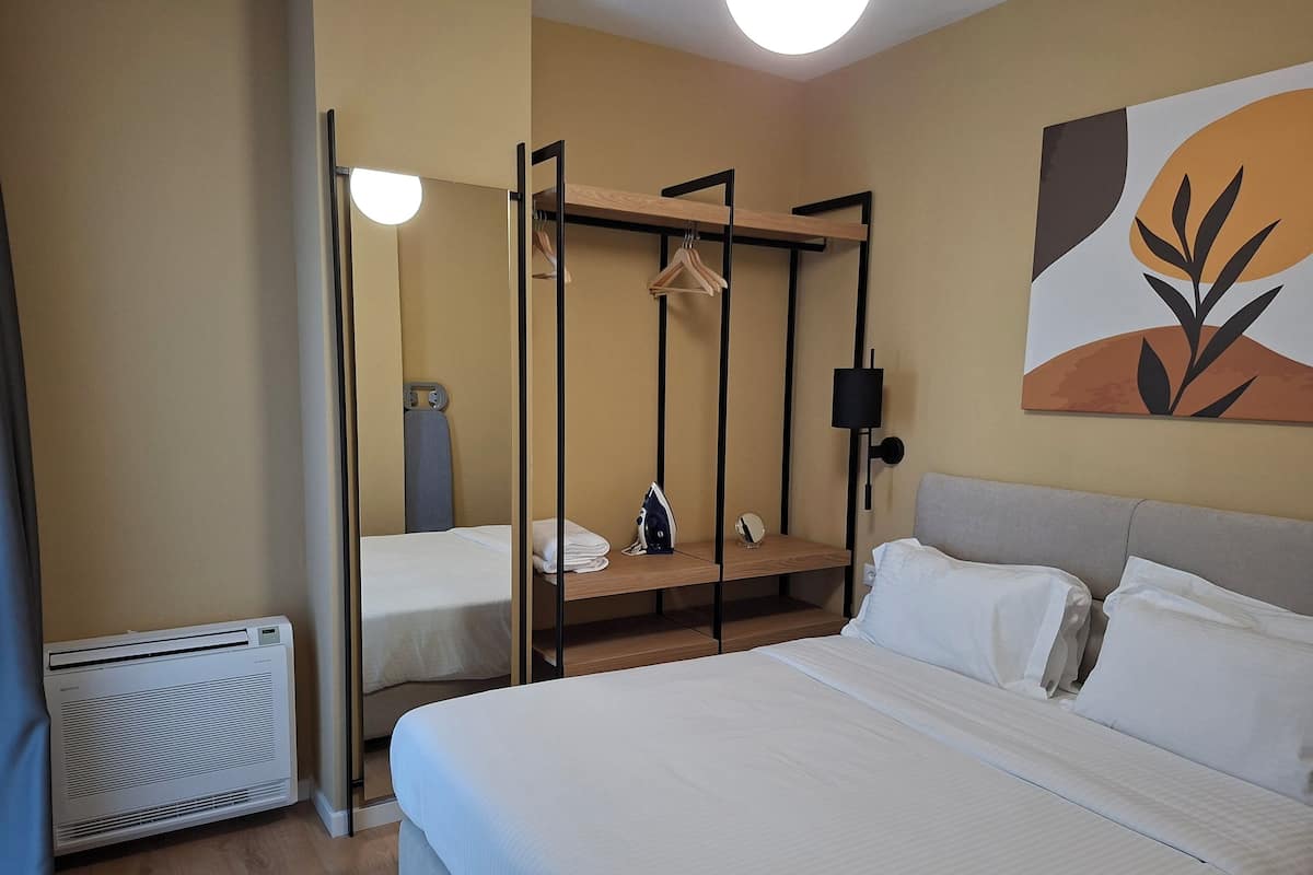 A hotel room with a large bed, a bedside table, a wardrobe with a mirror, and a radiator.