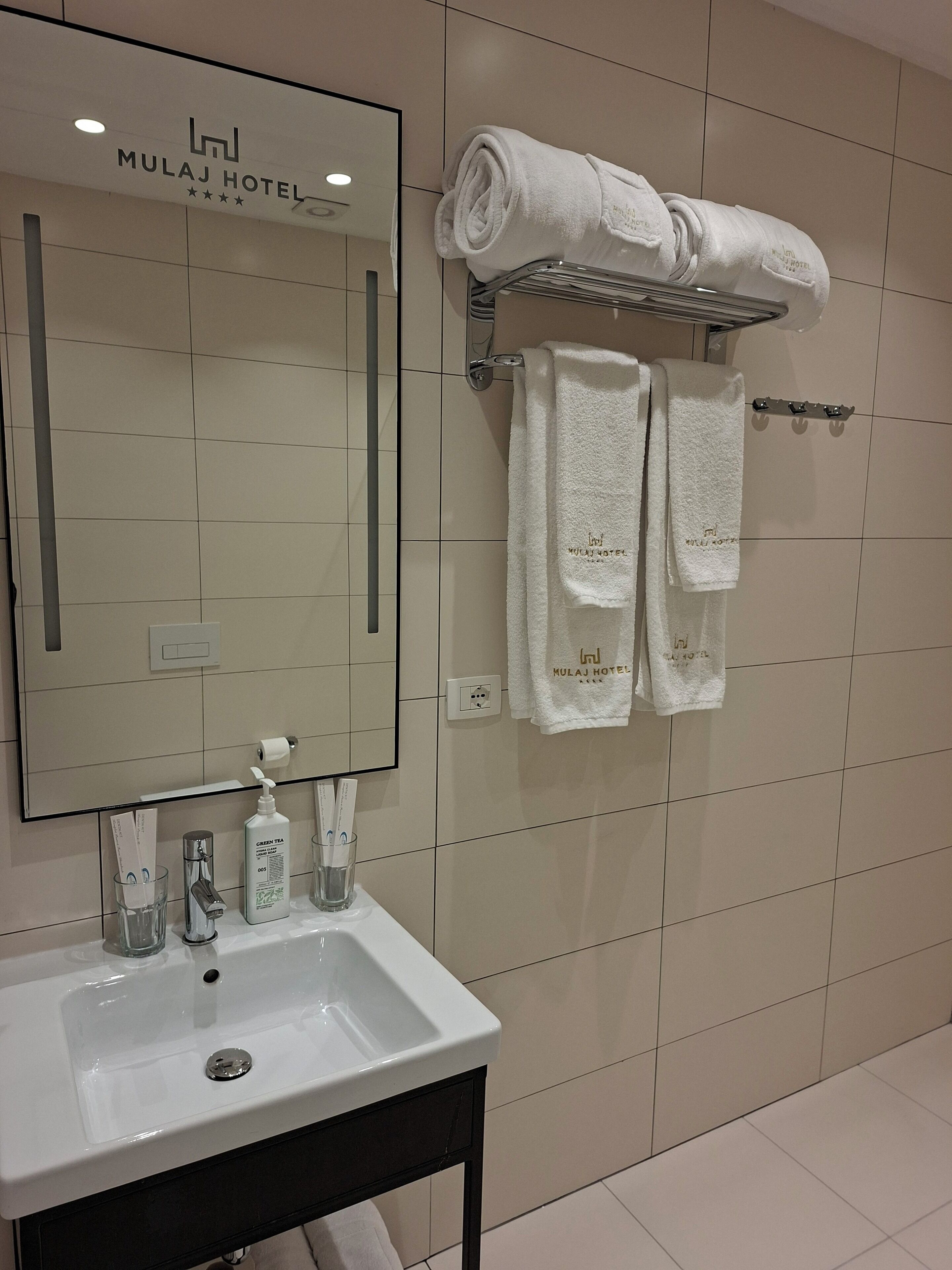 A bathroom with a white sink, mirror, and towel rack with towels.