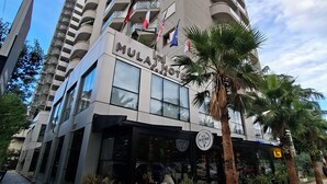 Un hotel llamado "MULATHOT" con una fachada moderna, varios balcones y un letrero para el restaurante "LIRAL BISTRO".