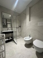 Un baño moderno con ducha envuelta en vidrio, un lavamanos y un inodoro.