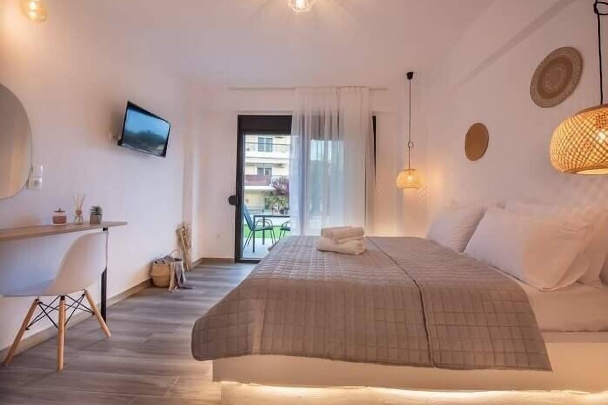 A bedroom with a bed, a desk, a TV, and a balcony with a view.