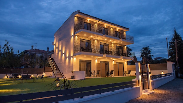 A multi-story residential building with balconies, outdoor seating, and a well-lit entrance. - Alios Gaia (Sithonia)