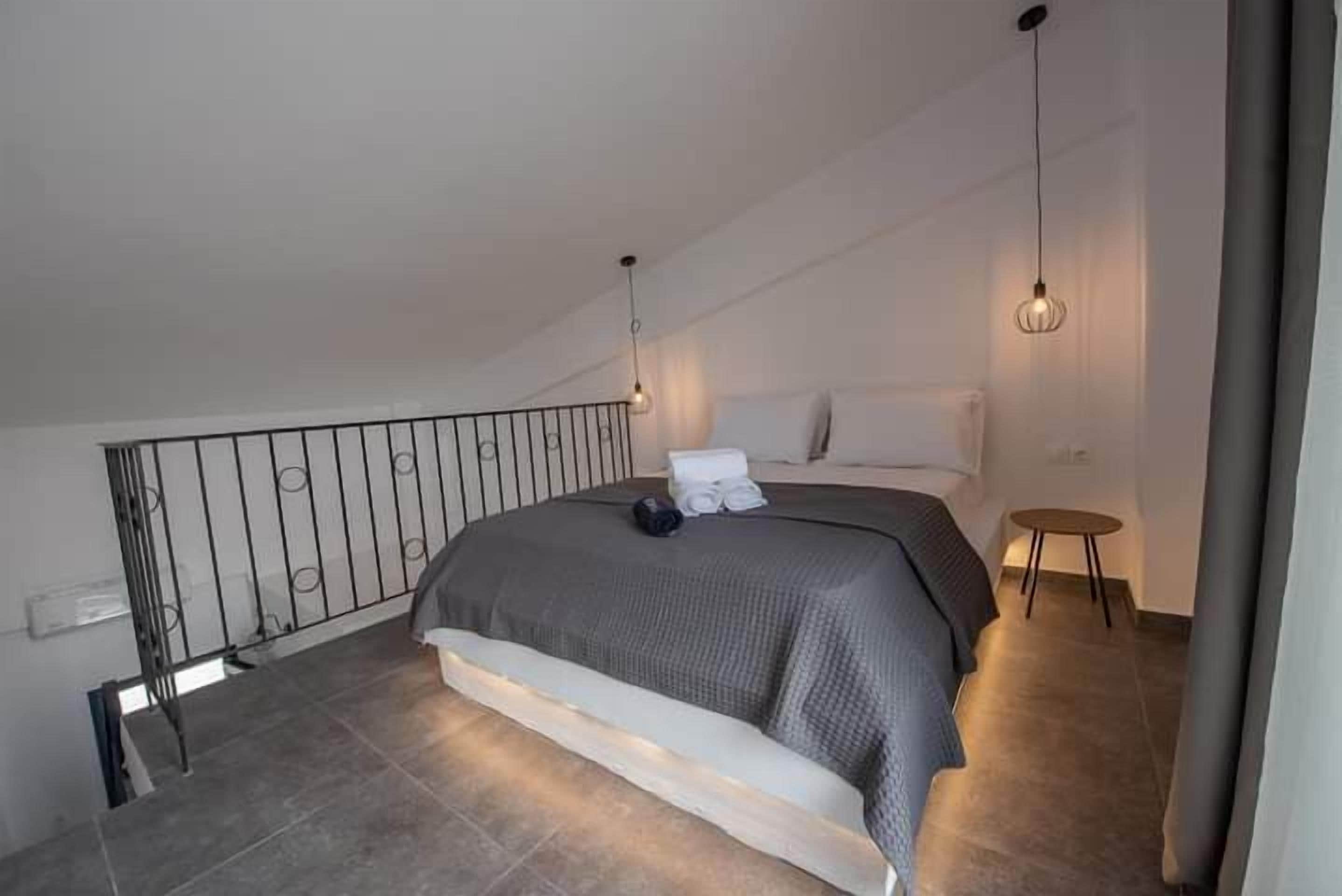Une chambre avec un grand lit, une petite table et un balcon doté d’une balustrade.