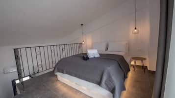 Une chambre avec un grand lit, une petite table et un balcon doté d’une balustrade.