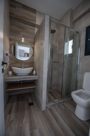 A modern bathroom with a freestanding sink, a glass-enclosed shower, and a toilet. - Alios Gaia (Sithonia)