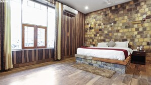 A bedroom with a large bed, wooden flooring, a stone wall, and a window with curtains. - 1B-Wild Heritage-102 N By bnbmehomes (Salt)