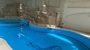 Une piscine ornée d’une mosaïque représentant un dauphin, un mur en pierre et un escalier pour y accéder.