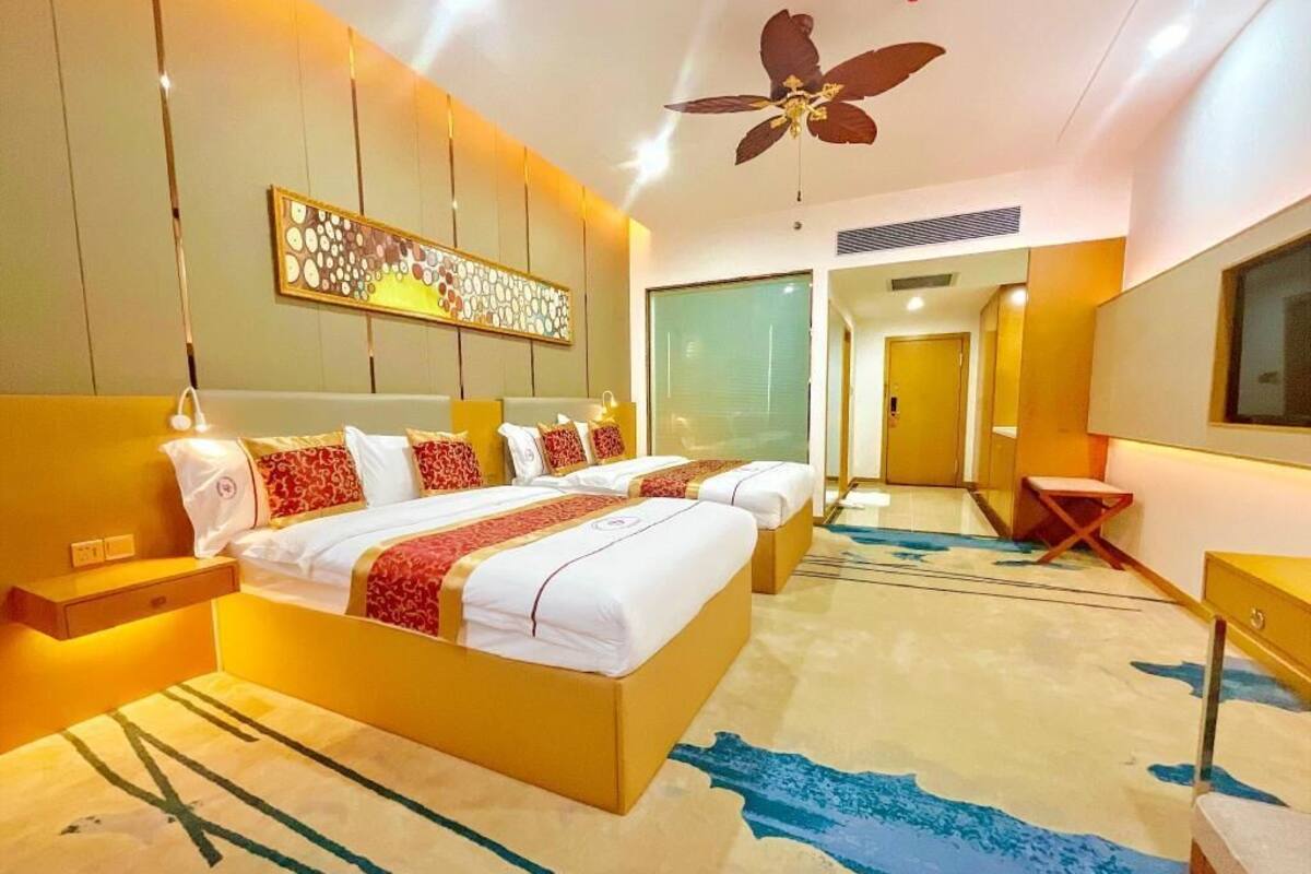 A hotel room with a large bed, bedside tables, a ceiling fan, and a view of the hallway.
