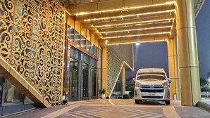 A modern building entrance with a white SUV parked inside. - ST Vegas Hotel (Hadxayfong)