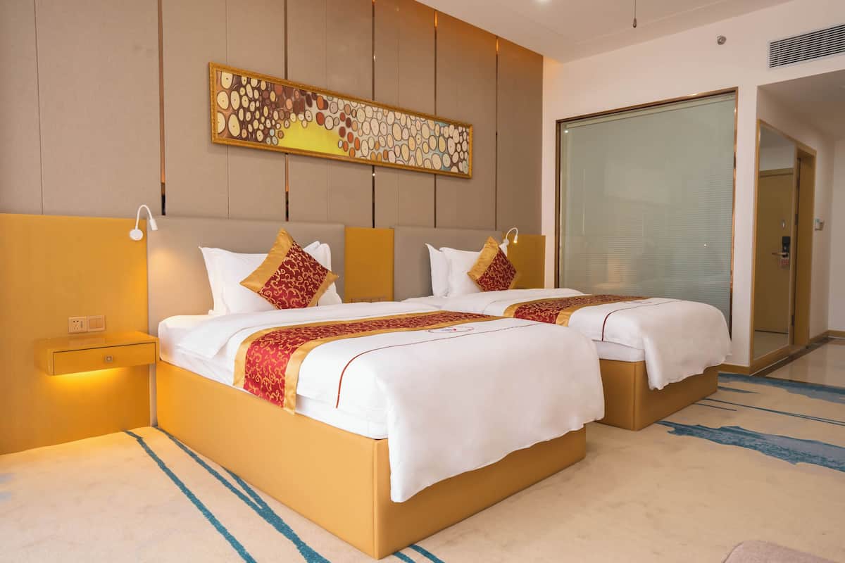 A hotel room with two beds, a large abstract painting, and a sliding glass door.