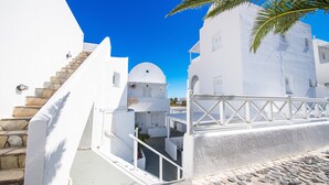 A white building with a stone staircase and a palm tree. - Aspro Phos (Santorini)
