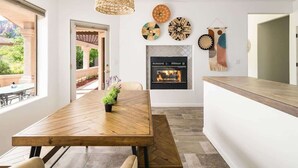 Une cuisine moderne avec une table à manger en bois, une cheminée et des œuvres d’art décoratives au mur.