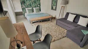 Un dormitorio moderno con cama, sofá, escritorio con lámpara y alfombra.