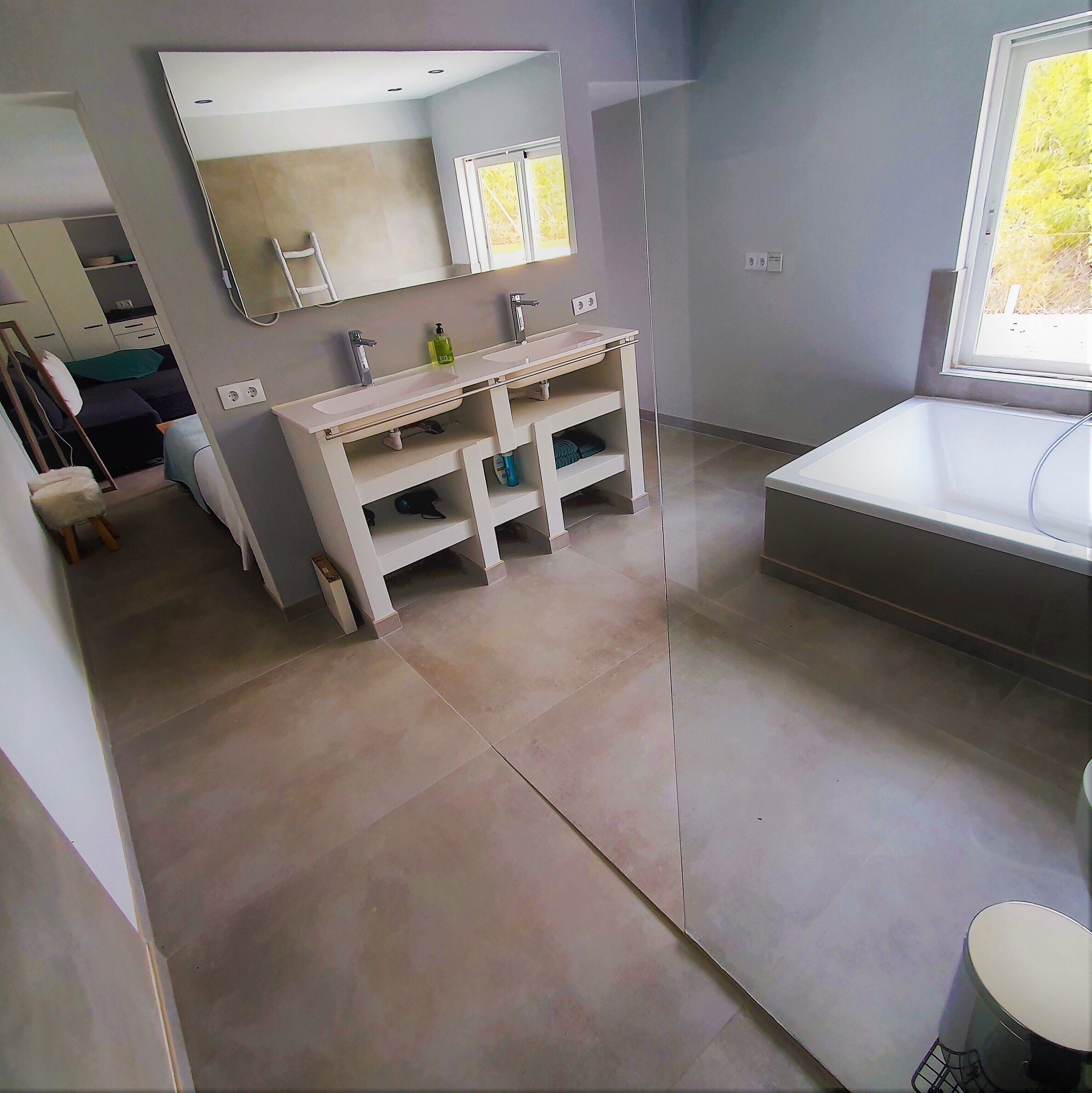 A modern bathroom with a large mirror, two sinks, and a bathtub.