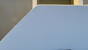 Una puerta con una lámpara encima, en un marco blanco sobre una pared gris.