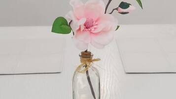 A clear glass vase with a pink flower arrangement on a white table.