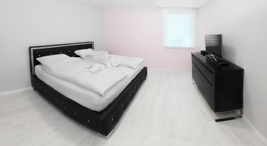 Un dormitorio con una cama, un aparador y un televisor.